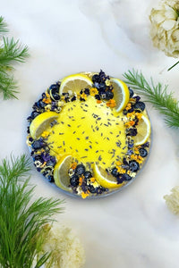 The cake is lavishly topped with fresh blueberries, juicy lemon wedges and a sprinkle of edible dried lavender buds for added elegance.